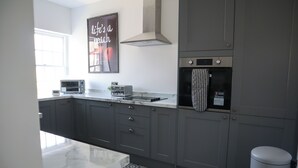 A modern kitchen with grey cabinets, a built-in microwave, a toaster, and a stainless steel range hood. - Knaresborough Retreat - Group Accommodation (Knaresborough)