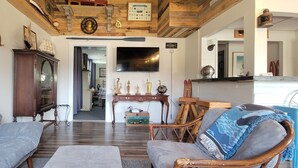 A living room with a wooden ceiling, a television, a cabinet, and a sofa.