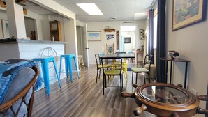 A dining area with a wooden table, blue chairs, and a ship's wheel decoration.