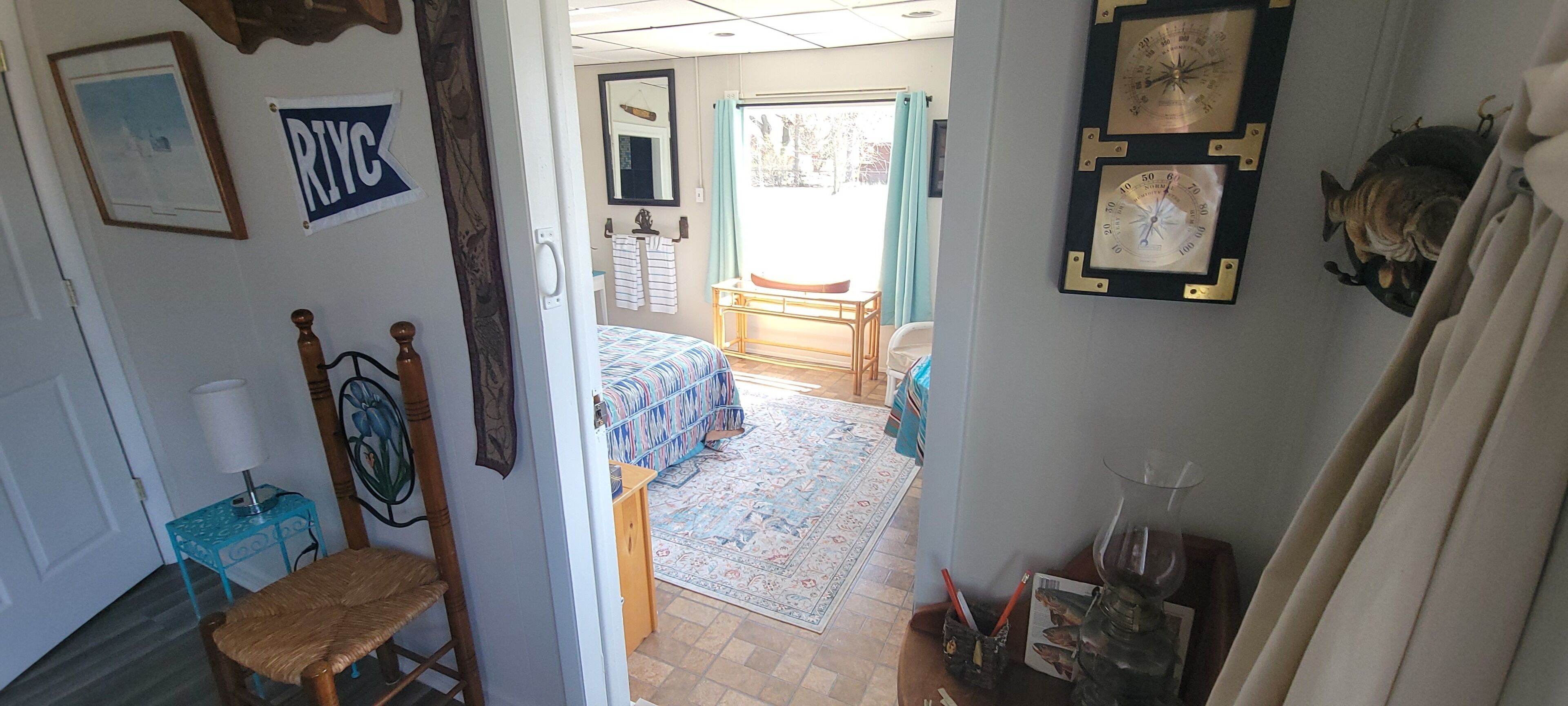 Une pièce comprenant un lit, une chaise, une petite table, un miroir et une horloge murale.