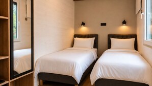 Une chambre avec deux lits, des poutres en bois, des murs blancs et deux lampes fixées au mur.