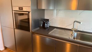 Une cuisine moderne équipée d’appareils électroménagers en acier inoxydable, d’un four encastré et d’une machine à café.