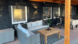 Un espace extérieur aménagé, abrité et doté d’un canapé, de chaises, d’une table et d’un plafond en bois.
