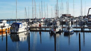 A marina with multiple boats docked at piers. - Cozy and barrier-free vacation apartment with balcony in Damp. Directly by the sea. (Thumby)