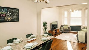 A dining area with a marble table, green chairs, and a framed map on the wall.