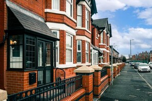 A row of red brick terraced houses with black window frames and white window sills.