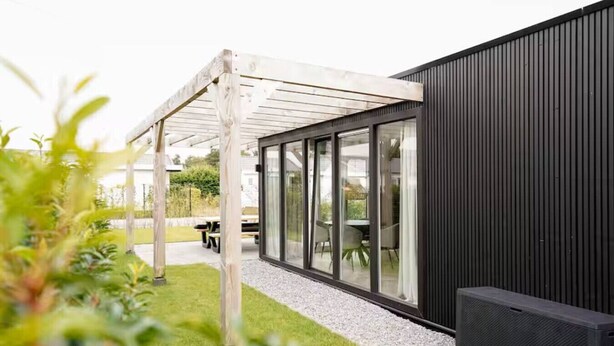 Un edificio moderno con una veranda coperta, ampie finestre e un vialetto in ghiaia.