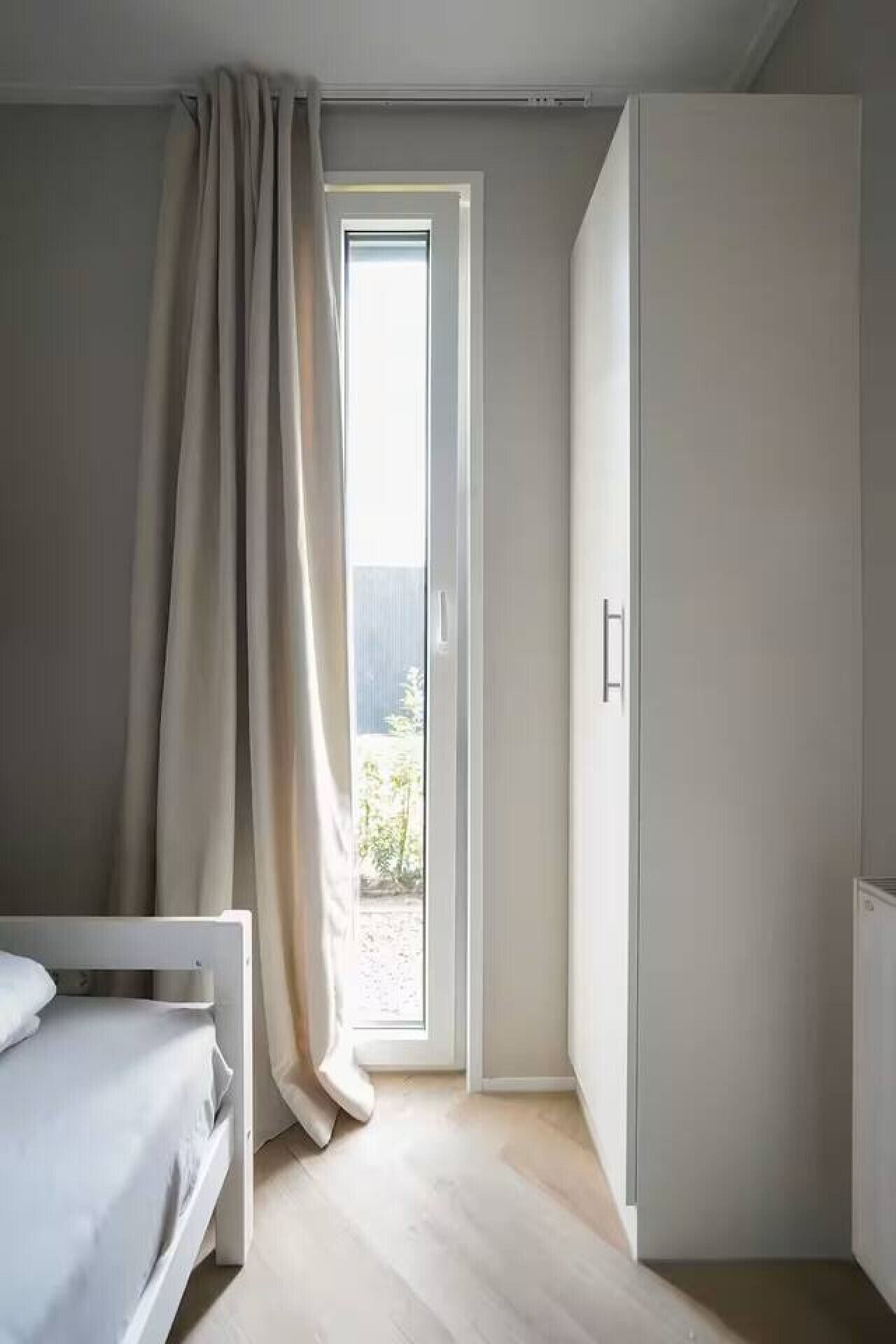A bedroom with a bed, a wardrobe, and a sliding glass door leading to an outdoor area.