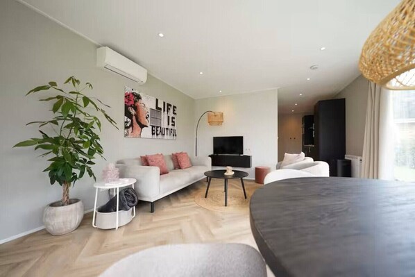 Un salon moderne avec un canapé, une table basse, un téléviseur et une plante en pot.