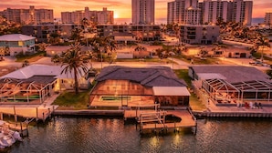 A coastal resort with modern buildings, a marina, and a sunset view.