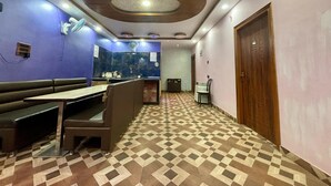 A hotel lobby with a check-in counter, seating area, and patterned floor.