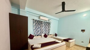 A bedroom with a bed, two bedside tables, a wardrobe, an air conditioning unit, and a ceiling fan.