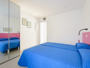 A bedroom with two beds, a large mirror, and a door leading to another room. - Colorful Property in Lignano (Lignano Sabbiadoro)