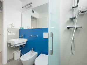 A modern bathroom with a bidet, a toilet, a sink, and a shower. - Colorful Property in Lignano (Lignano Sabbiadoro)