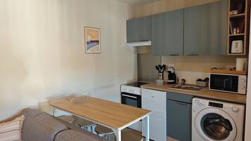 A compact kitchen with a dining area, a washing machine, and a microwave.