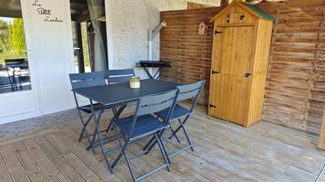 A patio with a table and chairs, a wooden cabinet, and a door with 'Le Petit Landais' text.