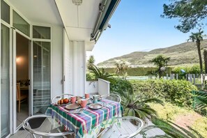 Ein Balkon mit Esstisch, eine Schiebetür und Blick auf eine hügelige Landschaft.