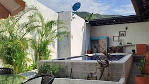 A patio area with a table and chairs, a satellite dish, and a view of a house with a pool.