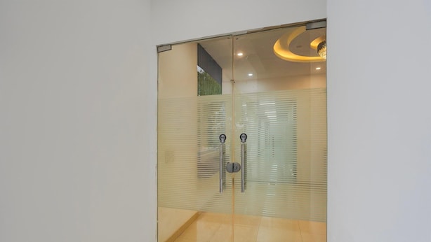 A glass door with a handle, a metal kick plate, and a ceiling light fixture.