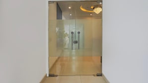 A modern room with a glass door, a chandelier, and a tiled floor.