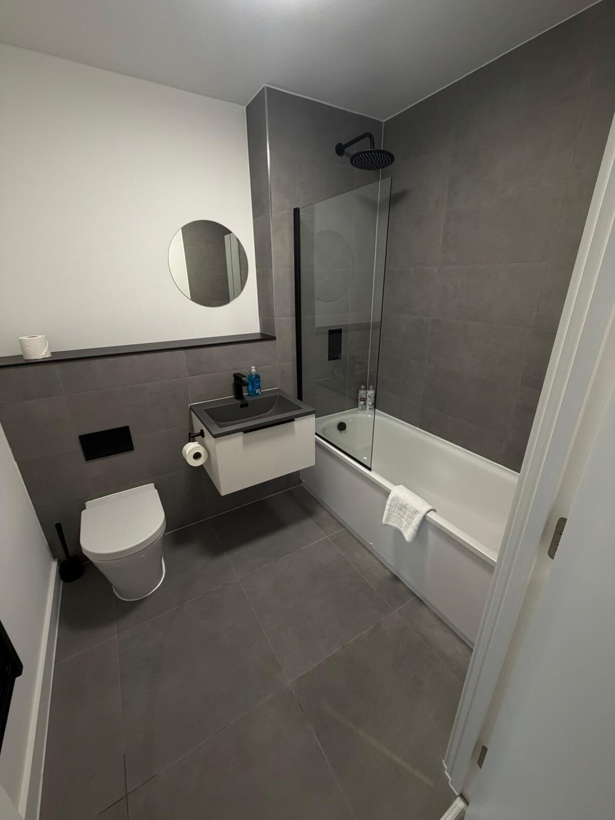 Ein modernes Badezimmer mit Toilette, Waschbecken, Spiegel und Dusche.