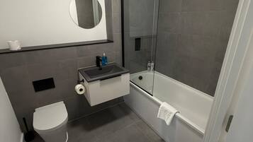 Ein modernes Badezimmer mit Toilette, Waschbecken, Spiegel und Dusche.