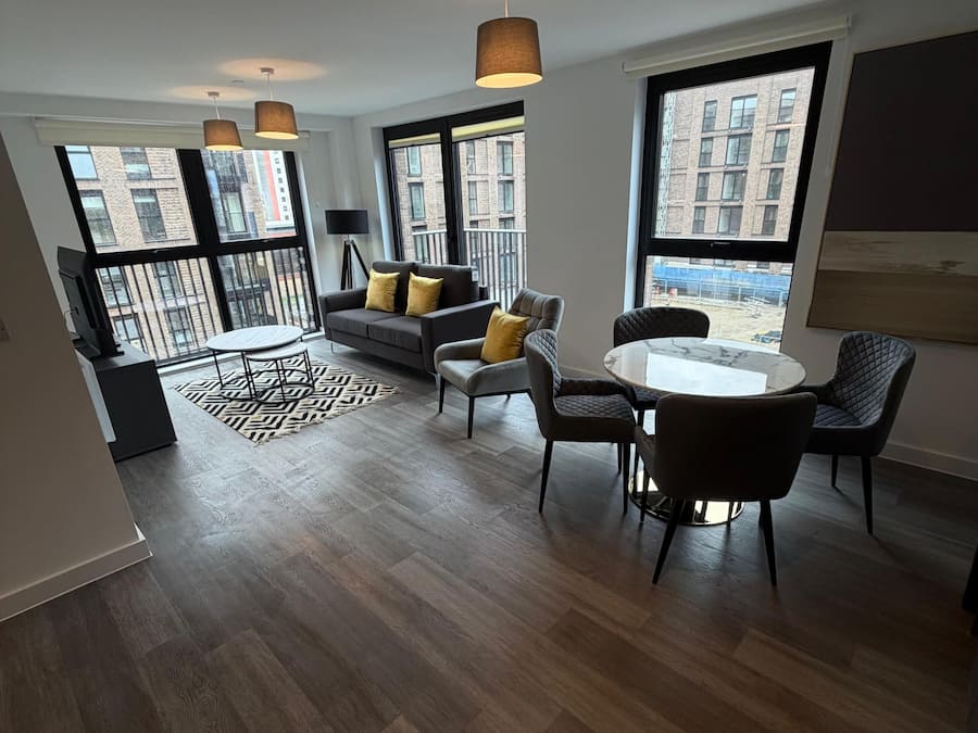 A modern apartment with a dining area, sofa, and large windows.