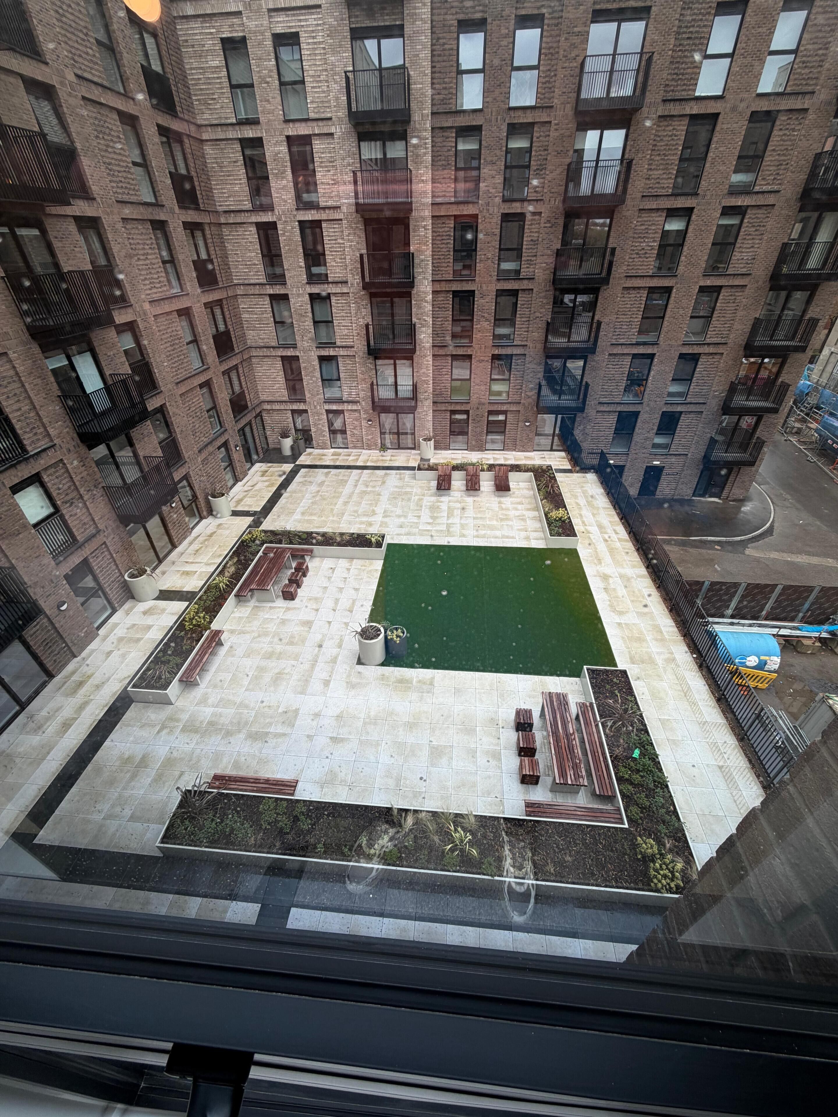 A high-rise building with a rooftop garden, multiple balconies, and a courtyard.