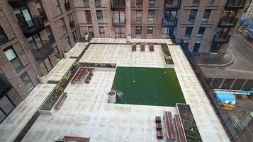 A high-rise building with a rooftop garden, multiple balconies, and a courtyard.