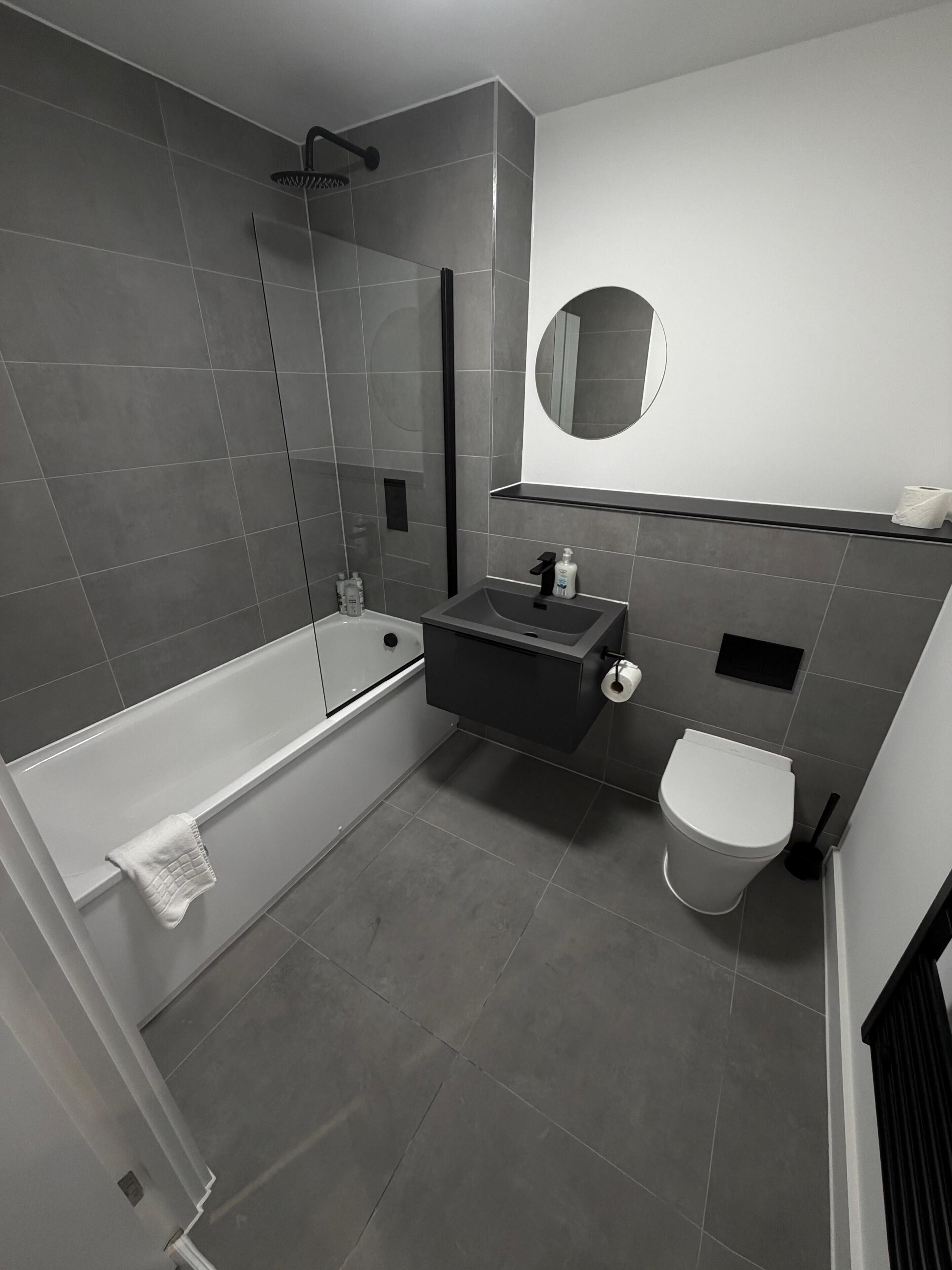 A modern bathroom with a bathtub, toilet, and sink.