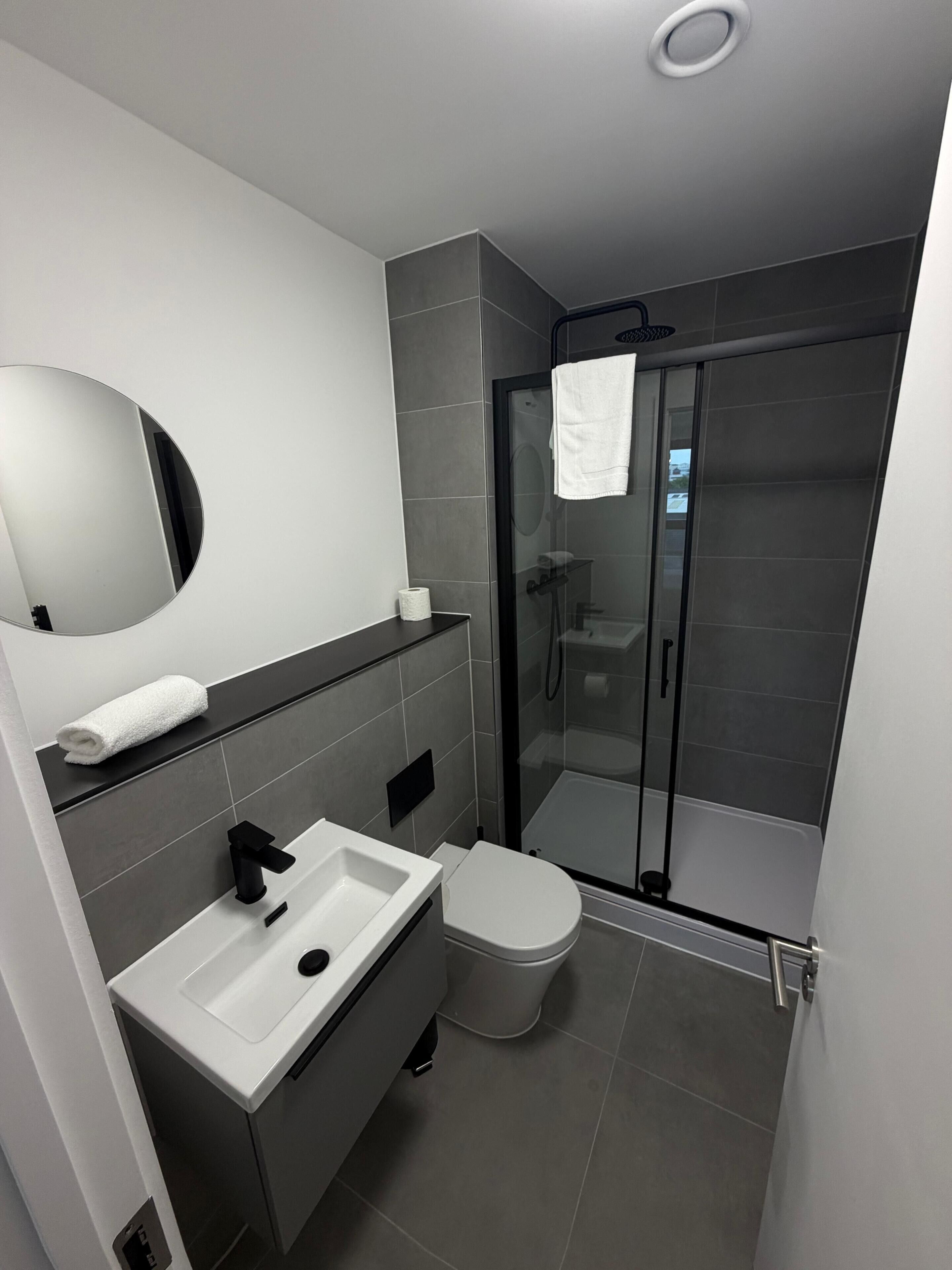 A modern bathroom with a sink, toilet, and glass-enclosed shower.