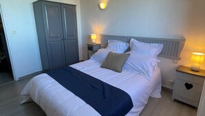 Ein Schlafzimmer mit Bett, Nachttischen, einem Kleiderschrank und einer Decke mit freiliegenden Balken.