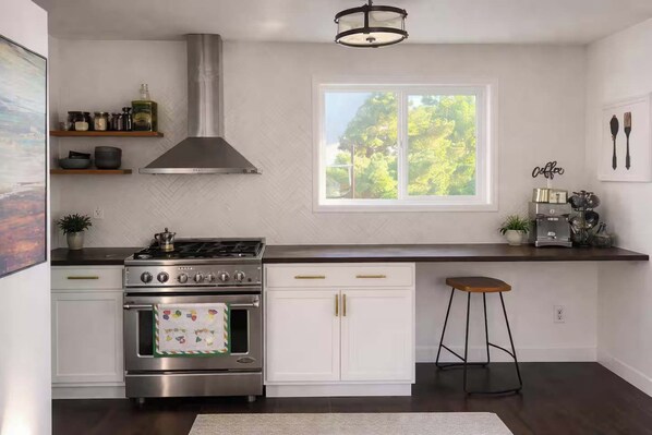 Een moderne keuken met een fornuis, oven en een raam met uitzicht op groen.