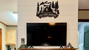 Una chimenea con un televisor encima, una señal sobre la chimenea y una planta en la repisa.