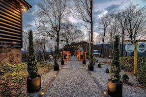 A pathway leading to a building with a stone facade, surrounded by trees and potted plants, with a QR code sign on the right. - Amazing Sunset+MountainViews+HotTub•Firepit•Games•Sleeps 8 (Sevierville)