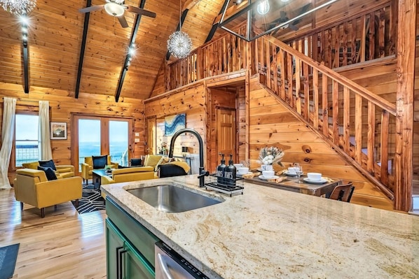 A wooden cabin interior with a kitchen, dining area, and a staircase. - Amazing Sunset+MountainViews+HotTub•Firepit•Games•Sleeps 8 (Sevierville)