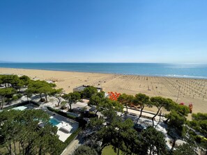 A beach resort with a swimming pool, beach area, and ocean view. - Seafront Apartment on the Promenade (Lignano Sabbiadoro)