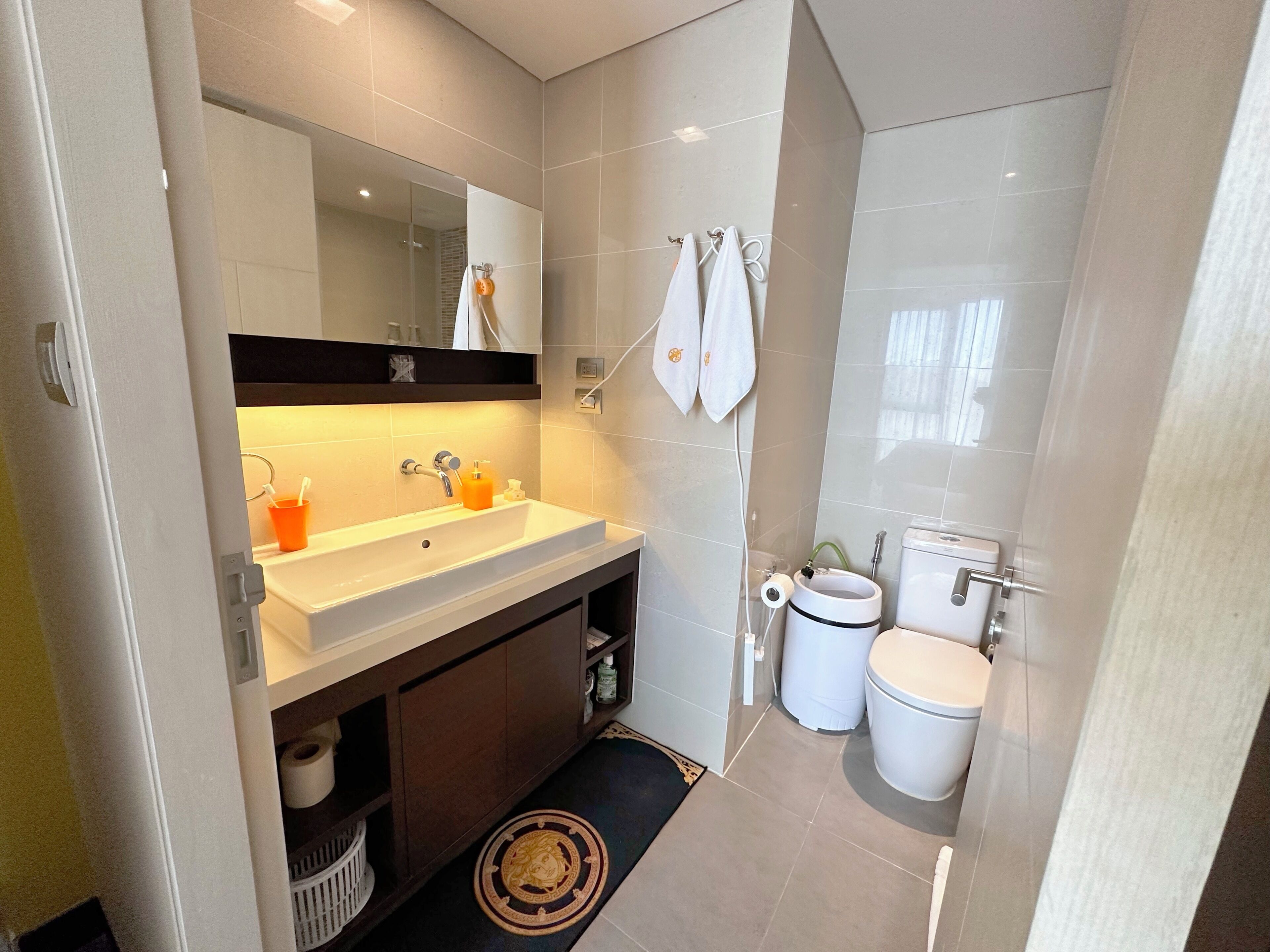 Een moderne badkamer met een wastafel, spiegel, handdoekrek, toilet en een bidet.