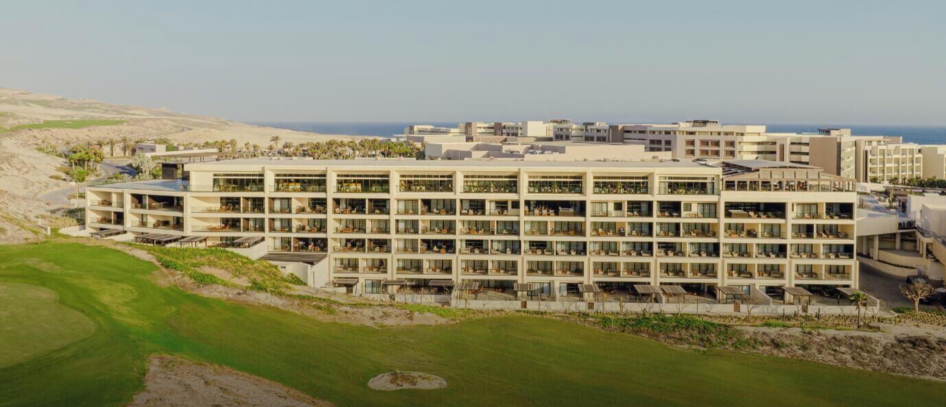 A multi-story hotel with a modern design, featuring balconies and large windows.