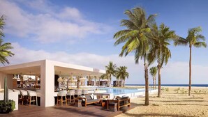Et moderne resort med pool, udendørs siddepladser og palmer.