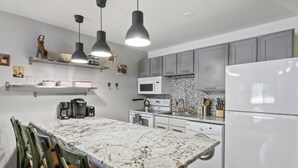 A modern kitchen with a marble countertop, built-in appliances, and pendant lighting. - Park City Snowcrest Chalet (Park City)