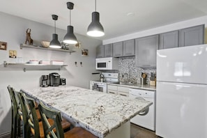 A modern kitchen with a marble countertop, built-in appliances, and pendant lighting. - Park City Snowcrest Chalet (Park City)