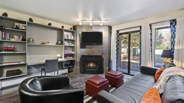 A living room with a fireplace, a television, a sofa, and a bookshelf. - Park City Snowcrest Chalet (Park City)