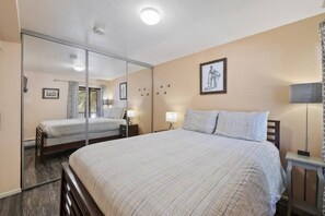 A bedroom with a large bed, a mirror, a bedside table with a lamp, and a picture on the wall. - Park City Snowcrest Chalet (Park City)