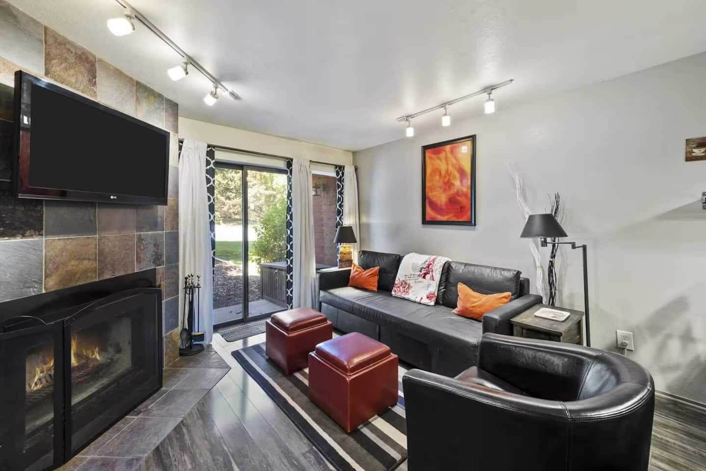 A modern living room with a fireplace, a sofa set, and a flat-screen TV.
