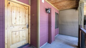 A wooden door with a number '115' on the wall beside it, a small wall-mounted light fixture, and a concrete floor. - Park City Snowcrest Chalet (Park City)