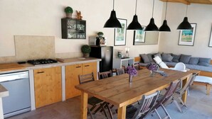 A modern kitchen with wooden cabinets, a dining table, and hanging pendant lights. - Charming Villa in Provence, Poolside Living & Cicada-Filled Evenings (LAURIS)