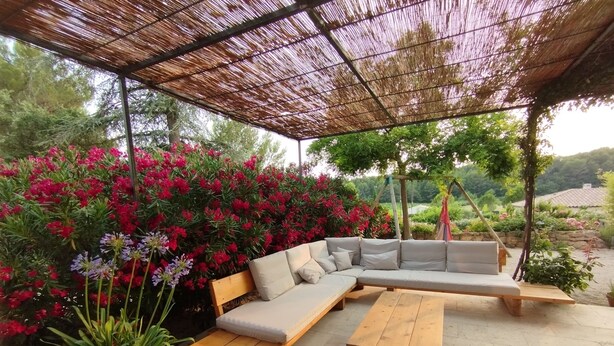 An outdoor seating area with a sofa, wooden tables, and potted plants. - Charming Villa in Provence, Poolside Living & Cicada-Filled Evenings (LAURIS)