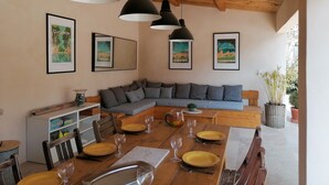 A dining area with a wooden table set for four, a gray sofa, and framed pictures on the wall. - Charming Villa in Provence, Poolside Living & Cicada-Filled Evenings (LAURIS)