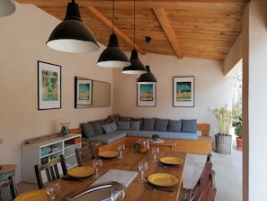 A dining area with a wooden table set for four, a gray sofa, and framed pictures on the wall. - Charming Villa in Provence, Poolside Living & Cicada-Filled Evenings (LAURIS)